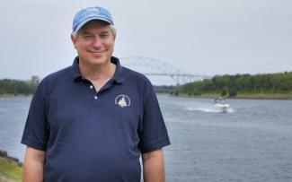 Dr. Glen Gawarkiewicz smiles at the camera in a light blue ball cap and a navy polo