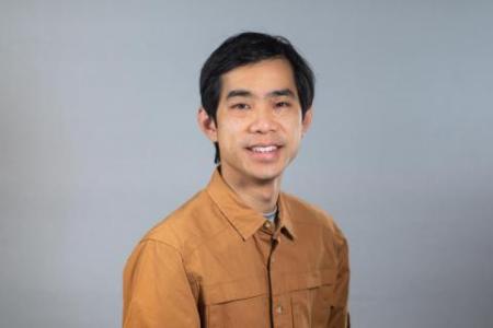 Dr. Edward Lo smiles at the camera in a tan button up. His hair is black and parted to the side. 