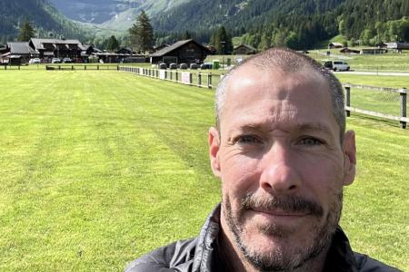 Dr. Cameron Thrash smiles in a selfie backed by a mountain range