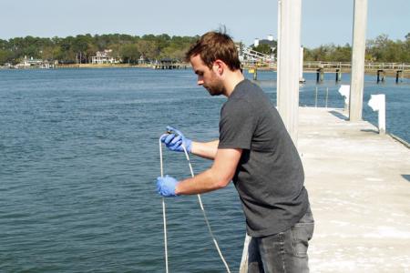 UGA Skidaway Institute grad student Sean Anderson collects a water sample from the Skidaway River. 