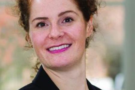 Dr. Jill McDermont smiles into the camera in a black blazer and pink shirt